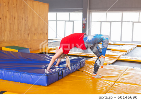 Young woman sportsman on a trampoline in fitness park and doing exercise indoors 60146690