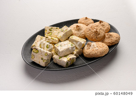 Nougat and almond cookies on a dark plate against a light background 60148049