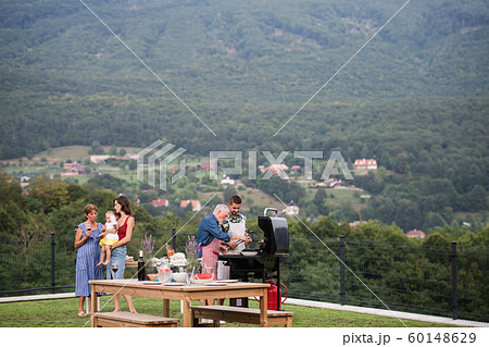 Multigeneration family with wine outdoors on garden barbecue, grilling. Multigeneration family with wine outdoors on garden barbecue, grilling. 60148629