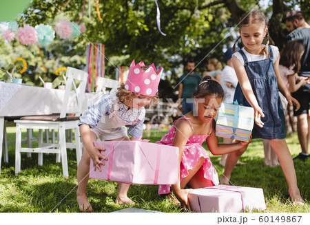 Small girls with presents outdoors in garden in summer, playing. 60149867