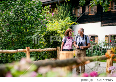 A senior pensioner couple with binoculars hiking, talking. 60149985