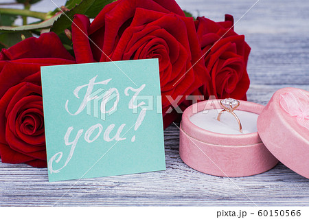 Engagement ring in box and red roses. 60150566