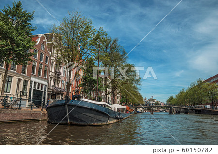 Old brick buildings near canal with moored boats in Amsterdam 60150782