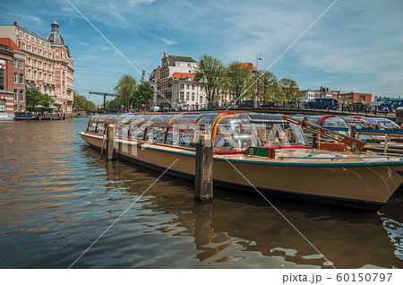 Boats moored at canal side and brick buildings in Amsterdam 60150797