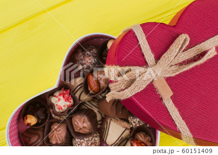 Red heart shaped gift box with chocolate candies. Red heart shaped gift box with chocolate candies. 60151409