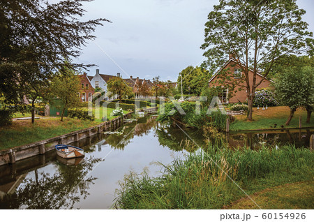 Canal next to rustic houses with gardens and trees Canal next to rustic houses with gardens and trees 60154926