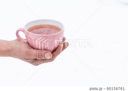 Hand holds a pink mug with a drink on a background 60156761