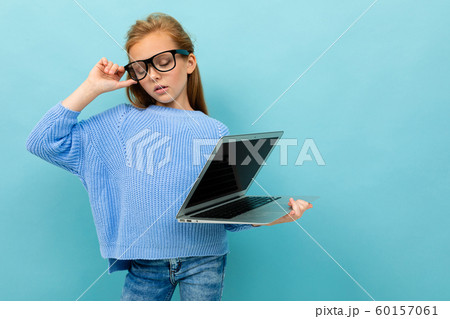 attractive european girl holding a computer in her hands with the screen forward on a light blue 60157061