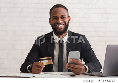 Cheerful afro man holding credit card, making purchases online 60158637