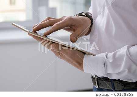 Hands of elegant businessman with tablet scrolling through online data Hands of elegant businessman with tablet scrolling through online data 60158858