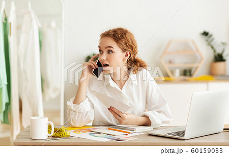 Young shop assistant talking on phone, discussing buyer's order 60159033