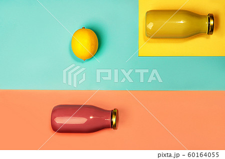 Bottles of multicolored juices or smoothies and lemon on yellow, pink coral and trendy mint green 60164055