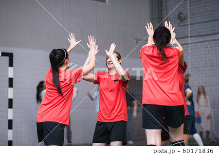Team of active girls in sports uniform expressing triumph by high-five gesture 60171836