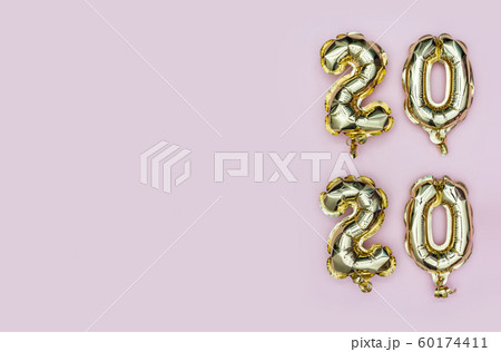 New Year 2020. Vertical composition of number 2020 golden foil balloons on pastel pink background 60174411