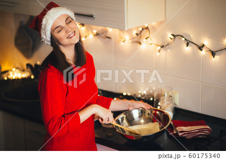 Happy woman in Santa hat cooking Christmas cookies 60175340