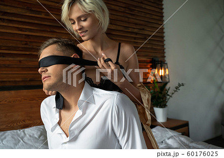 Pretty lady is using black tie in bedroom 60176025