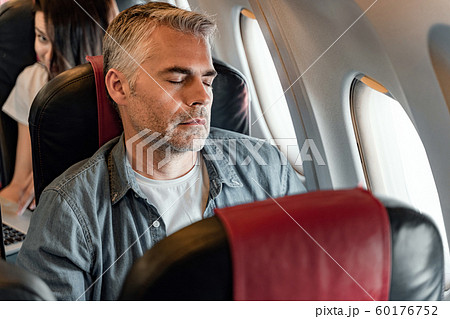 Adult man is sleeping near window in plane 60176752