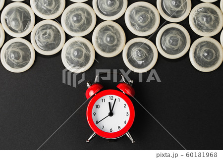 red alarm clock with condoms on black background red alarm clock with condoms on black background 60181968