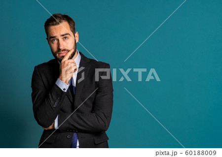Serious thinking businessman looking around on blue background. Confused pensive face expressions. Handsome male model in corporate suit. 60188009