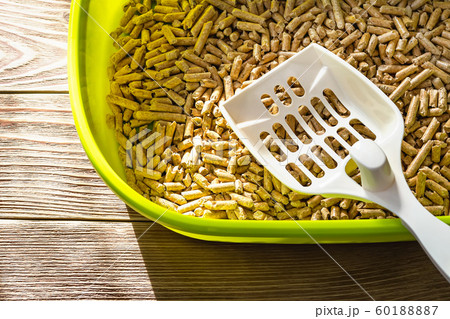 White scoop on a wooden pellets in a green cat litter box. White scoop on a wooden pellets in a green cat litter box. 60188887