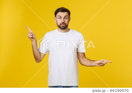 Handsome man over isolated yellow wall frustrated and pointing to the front. 60190070