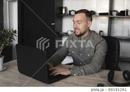 Happy Smile Young businessman or student in a shirt sitting against monitor of computer. Working on a pc at a table in the office with a thoughtful expression. 60191261
