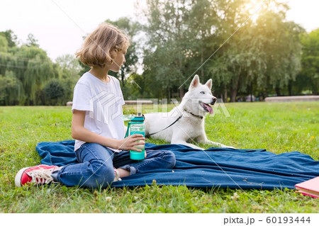 Little girl with a dog in the park sits on the grass, plays, reads, resting Little girl with a dog in the park sits on the grass, plays, reads, resting 60193444