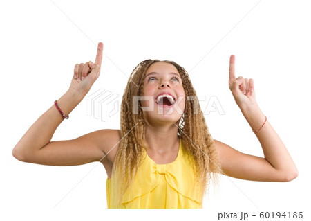 Happy blonde with curly hair, teen girl pointing her index finger up, indicating copy space on white blank wall for your content or information, isolated Happy blonde with curly hair, teen girl pointing her index finger up, indicating copy space on white blank wall for your content or information, isolated 60194186