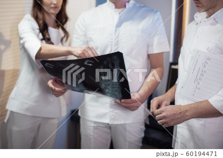 Three doctors look at an x-ray photo of a patient together 60194471