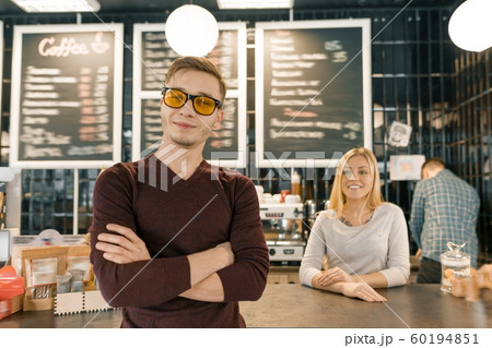 Young team of three cafe workers, people posing and smiling at coffee bar near bar counter. Teamwork, staff, small business, people concept 60194851