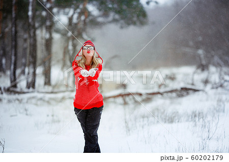 A woman in a red sweater in winter enjoys life in a snowy glade A woman in a red sweater in winter enjoys life in a snowy glade 60202179