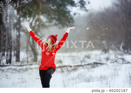 A woman in a red sweater in winter enjoys life in a snowy glade A woman in a red sweater in winter enjoys life in a snowy glade 60202187