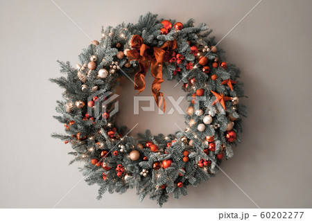 Beautiful festive wreath of fresh spruce on Gray wall. Xmas circlet with red and gold ornaments and balls. Christmas mood. Beautiful festive wreath of fresh spruce on Gray wall. Xmas circlet with red and gold ornaments and balls. Christmas mood. 60202277