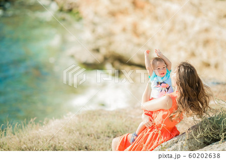 Young beautiful mom with baby in her arms on the seaside Young beautiful mom with baby in her arms on the seaside 60202638