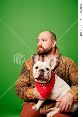 Man with beard looking to side with french bulldog in his arms Man with beard looking to side with french bulldog in his arms 60206064