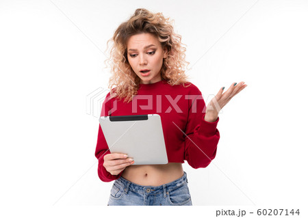 European girl reads messages on a tablet on a white studio background 60207144
