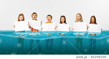 Group of children with blank white banners standing in water of melting glacier, global warming 60209200