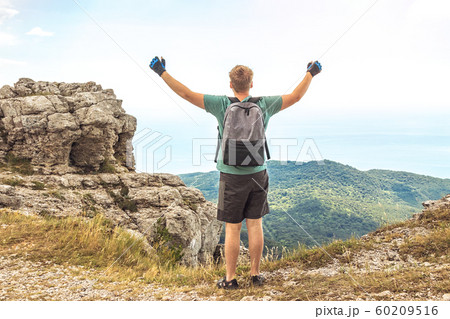 Young man with a backpack on top of cliff enjoying Young man with a backpack on top of cliff enjoying 60209516