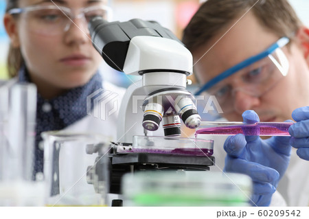 Male and female chemist research pink liquid 60209542