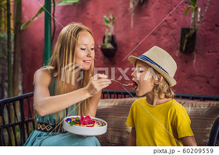 Mother and son having a mediterranean breakfast seated at the sofa and eats Healthy tropical 60209559