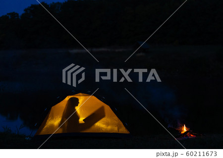 girl camping in the wilderness. Silhouette of a girl camping in the wilderness. Silhouette of a 60211673