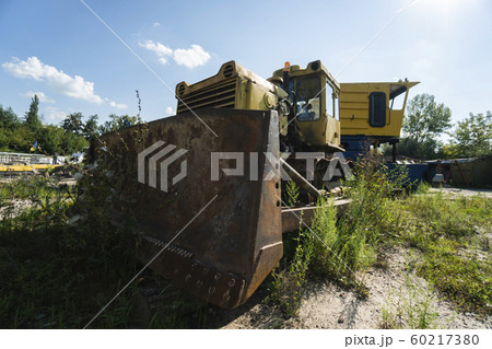 Old yellow rusty tractor in field in sunny day. 60217380