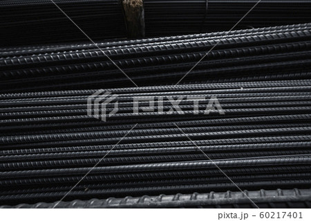 Building armature in the warehouse of metallurgical products or on construction site. Stack of heavy metal reinforcement bars with periodic profile texture. Steel construction armature. 60217401
