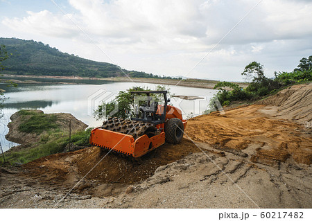 Soil compactor with vibratory padfoot drum. Heavy duty machinery working on highway construction site. Vehicle for soil compaction. Road construction equipment. Paving. Compaction of the road. Soil compactor with vibratory padfoot drum. Heavy duty machinery working on highway construction site. Vehicle for soil compaction. Road construction equipment. Paving. Compaction of the road. 60217482