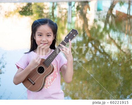 Little asian child girl play the ukulele, in the 60221915