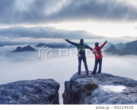 Couple on mountain looking over heavy mist to Couple on mountain looking over heavy mist to 60224916