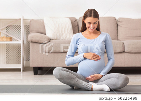 Smiling pregnant girl holding hands on her belly Smiling pregnant girl holding hands on her belly 60225499