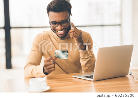 African man talking on phone holding credit card African man talking on phone holding credit card 60225500
