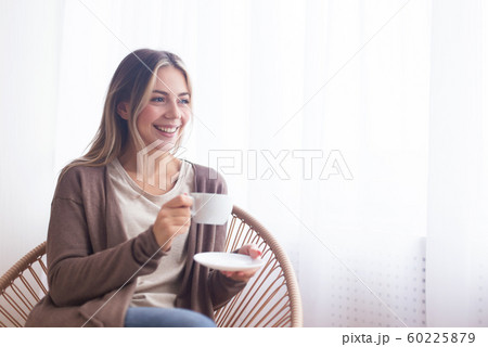 Cheerful girl enjoying hot drink at home 60225879