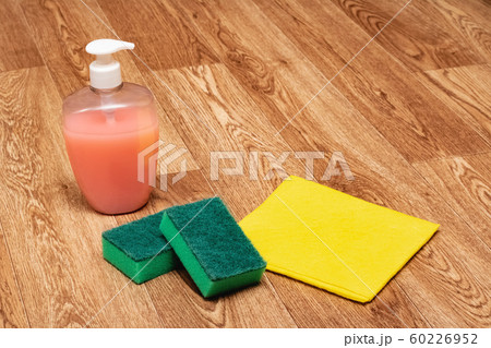 Cleaning agent, sponge and yellow rag on wooden 60226952